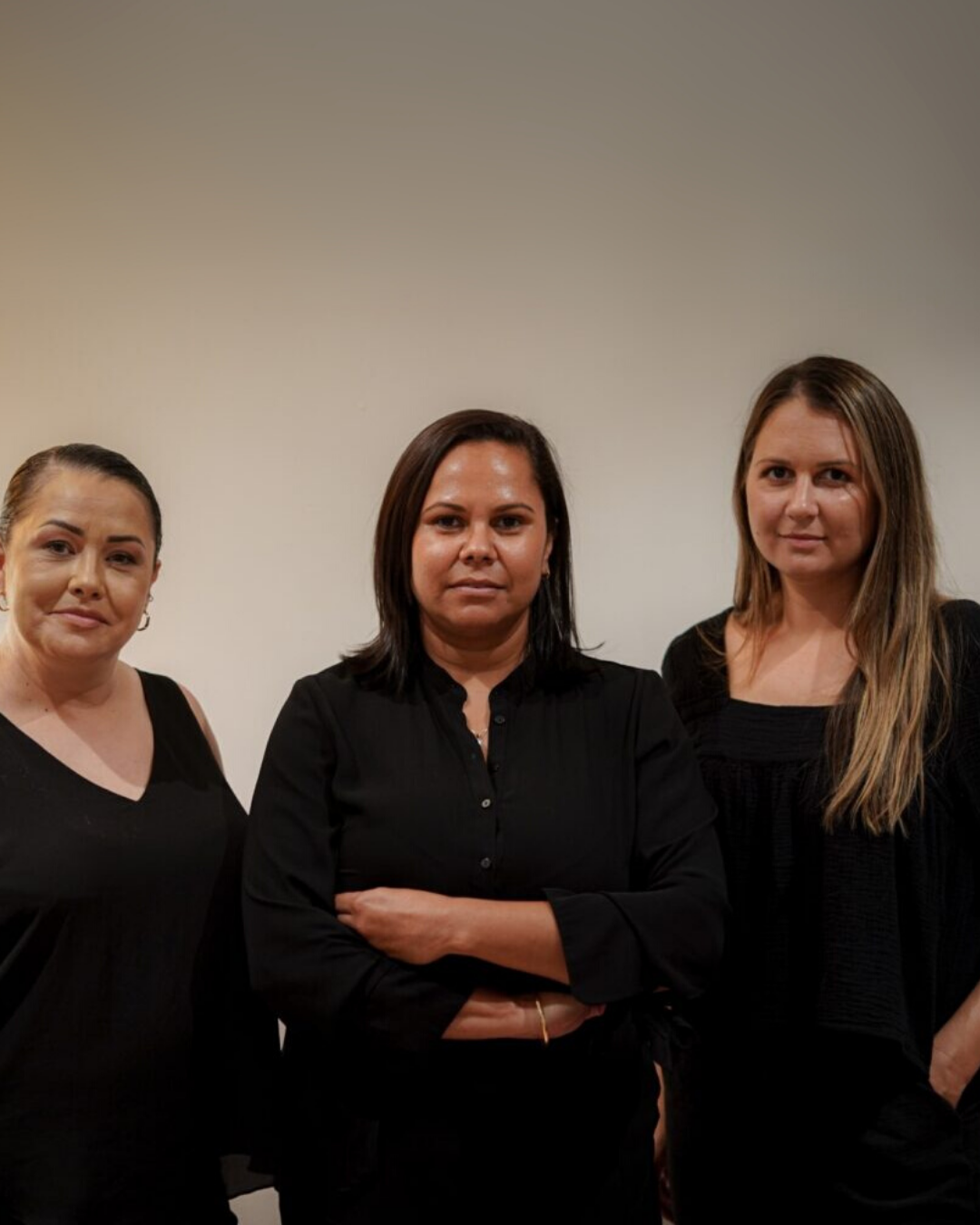 Three women in black standing with arms crossed